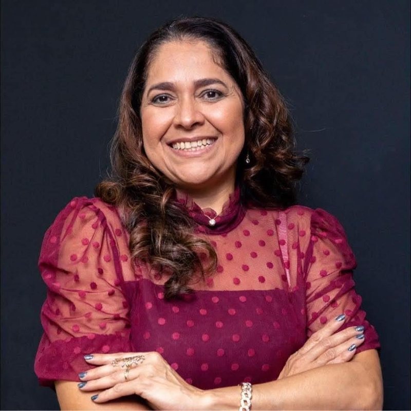 Malka Pestana Albuquerque sorrindo, de braços cruzados